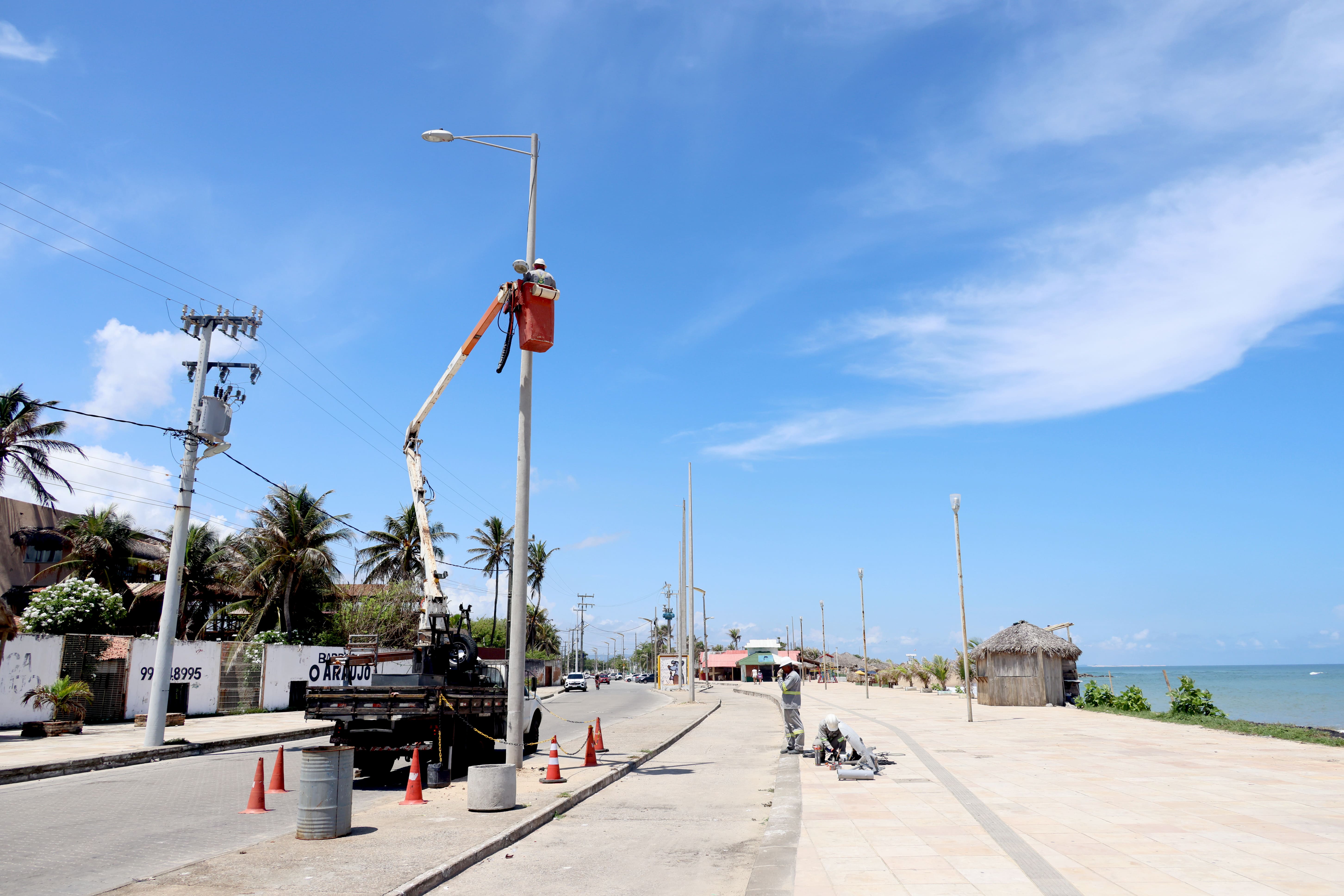 homens trocando as lâmpadas de um poste na avenida  vila do mar